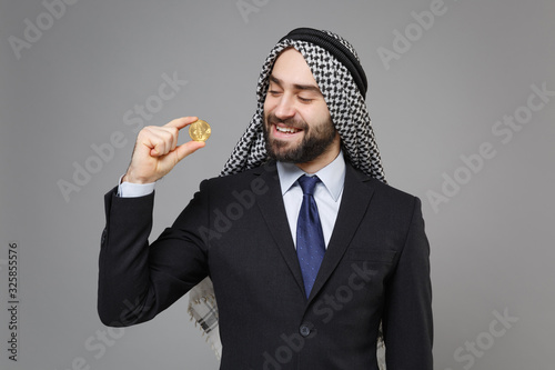 Photography Smiling young bearded arabian muslim businessman in keffiyeh kafiya ring igal agal classic suit isolated on gray background