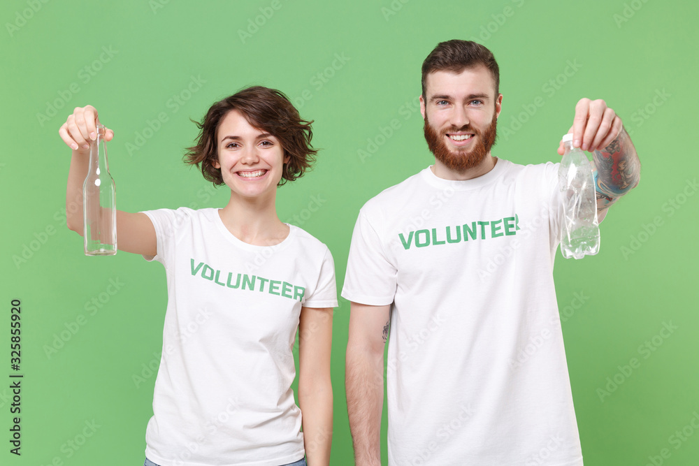 Smiling two young friends couple in volunteer t-shirt isolated on pastel green background. Voluntary free work assistance help charity grace teamwork concept. Hold trash empty plastic glass bottles. Smiling two young friends couple in volunteer t-shirt isolated on pastel green background. Voluntary free work assistance help charity grace teamwork concept. Hold trash empty plastic glass bottles.