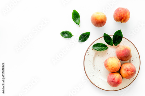 Summer fruits. Ripe red peaches on plate on white table top-down copy space