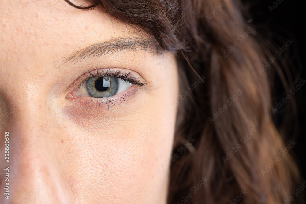 Fototapeta premium Half face of a gorgeous girl with blue eye in the foreground