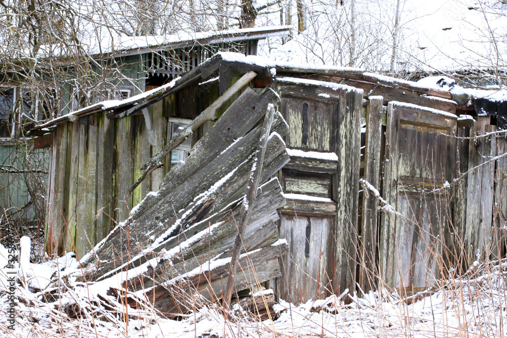 old ruined wooden barn building in a european village in winter weather, poor management