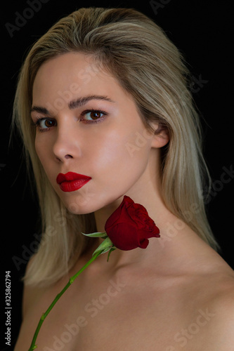 beautiful girl posing with a red rose on a dark background