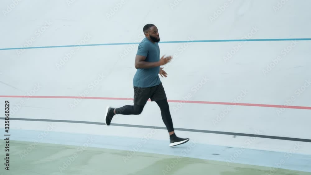 Young man running on sport track at stadium. Active athlete jogging outdoors