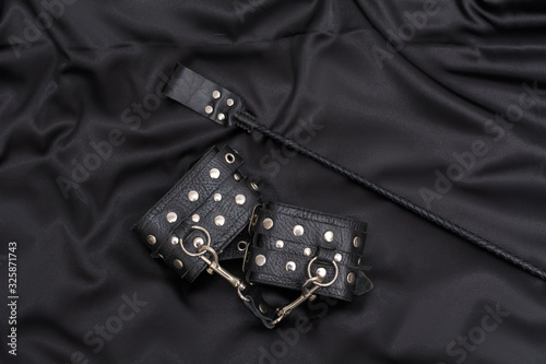 Leather handcuffs and stack on black background. Accessories for adult