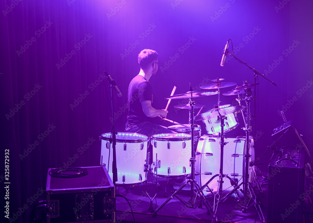 A young drummer playing on his percussion instrument in a fantastic light A young drummer playing on his percussion instrument in a fantastic light