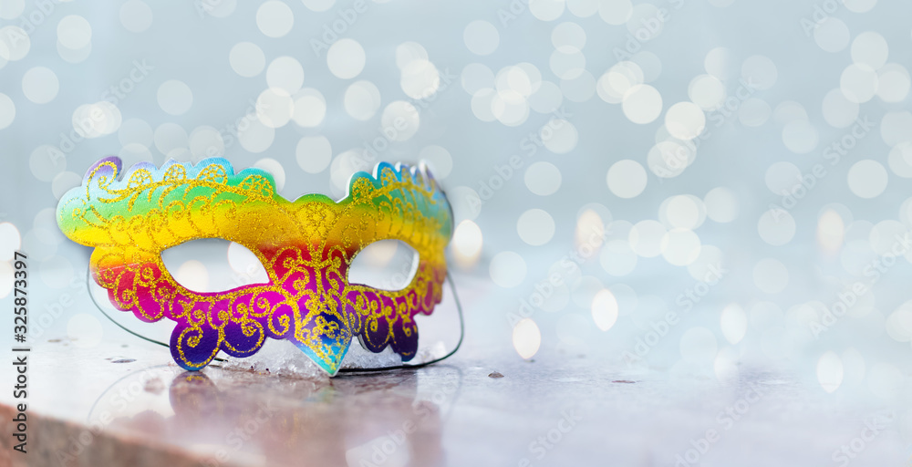 Brazilian or Venetian carnival.Bright multicolored mask on a bright shiny background with lights and bokeh.holiday.Carnival outfit.Celebration.Banner.Flat lay.Top view.Copyspace