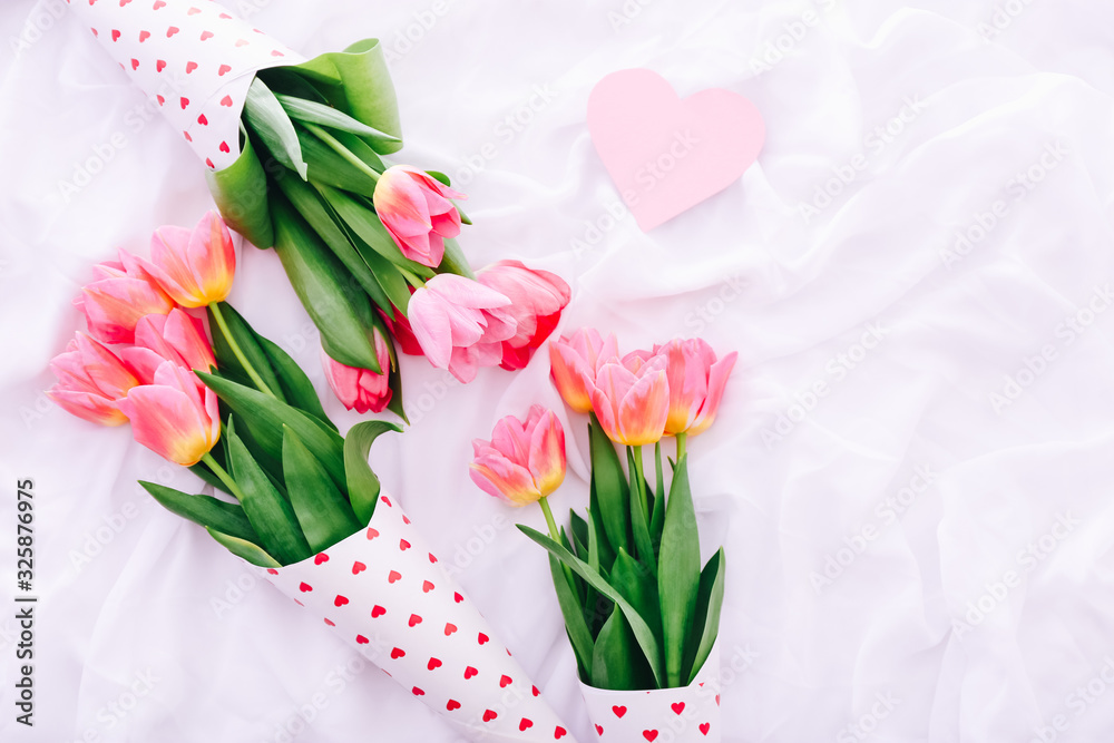 Obraz premium Three little bouquets of pink tulips on white bed.