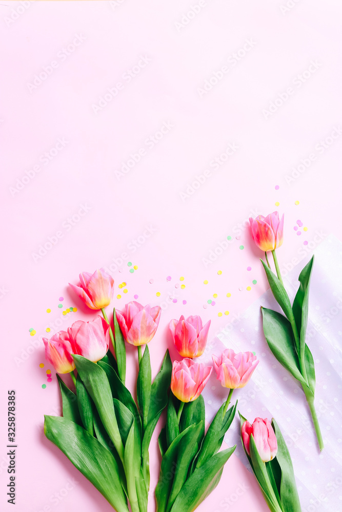Fototapeta premium Pink tulip flowers and confetti on pink background. Flat lay, Top view.