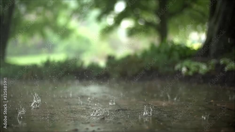 Fascinating close up steady satisfying slow motion shot of downpour rain drops falling on pavement asphalt concrete road Fascinating close up steady satisfying slow motion shot of downpour rain drops falling on pavement asphalt concrete road