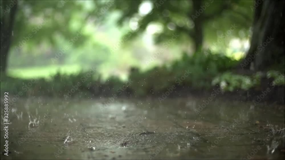 Magnificent steady close up satisfying slow motion shot of downpour rain drops falling on pavement asphalt concrete road Magnificent steady close up satisfying slow motion shot of downpour rain drops falling on pavement asphalt concrete road