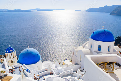 Blue domed church and traditional white houses facing Aegean Sea in Oia, Santorini, Greece