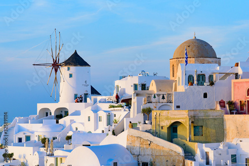 Windmill and traditional white buildings in sunset light in Oia, Santorini, Greece