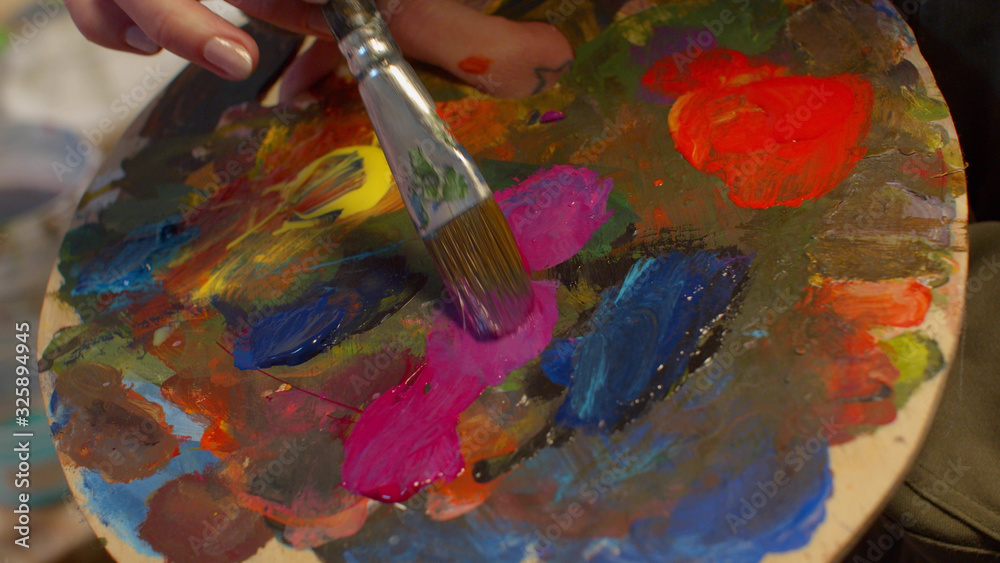 Obraz premium Woman mixes paints on the art palette