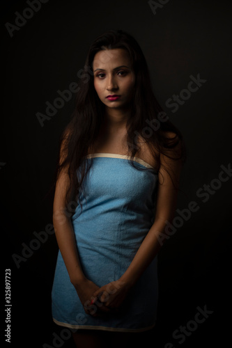 Portrait of Asian/Japanese/Korean/Indian brunette young girl in blue bath towel  in black studio copy space background. Indian lifestyle and fashion photography