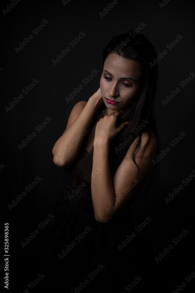 Fashion portrait of young and attractive Indian Bengali brunette girl in black western dress in front of black studio background. Indian lifestyle. Fashion portrait of young and attractive Indian Bengali brunette girl in black western dress in front of black studio background. Indian lifestyle.