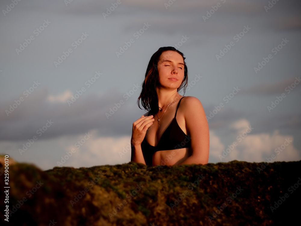 Young woman sitting in bath of sea water. Bali travel concept. Melasti beach