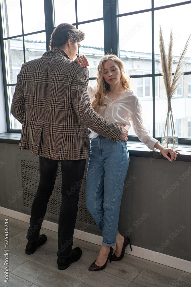 Beautiful young girl standing next to the window with boyfriend.