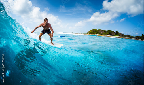 Canvas Print Young athletic surfer rides the ocean wave on Sultans surf spot in Maldives