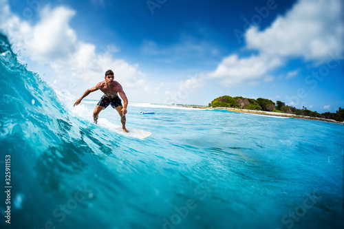 Young athletic surfer rides the ocean wave on Sultans surf spot in Maldives. Tilt shift effect applied © Dudarev Mikhail