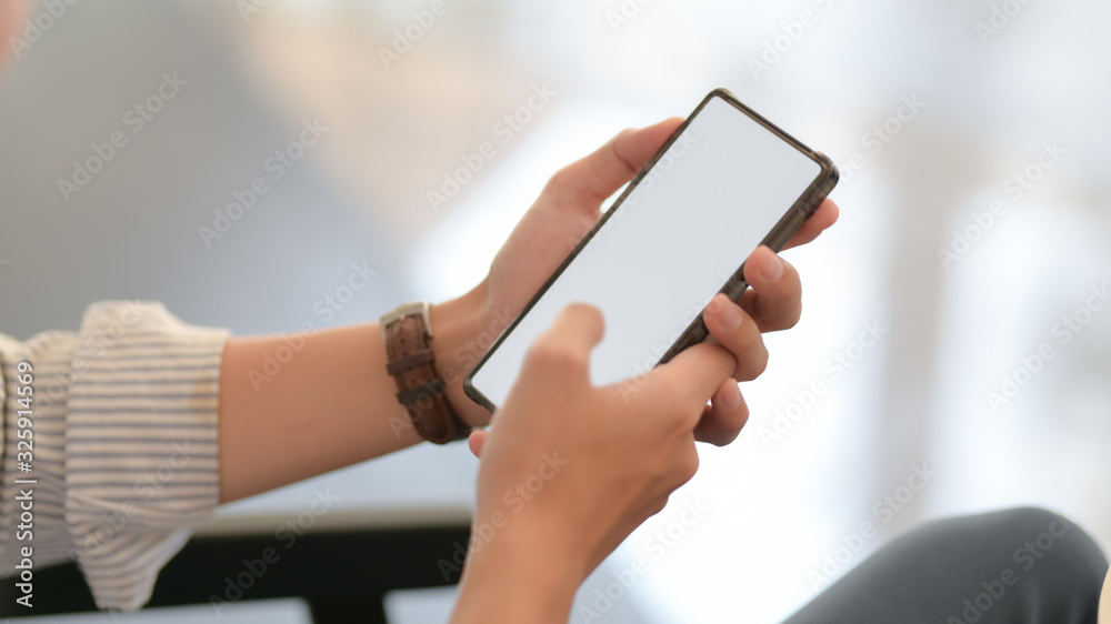 Close up view of businessman texting on smartphone while sitting on couch Close up view of businessman texting on smartphone while sitting on couch