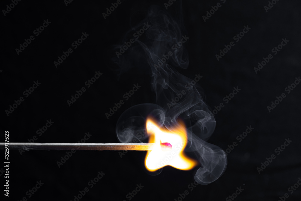 burning match with a bright flame against a black background