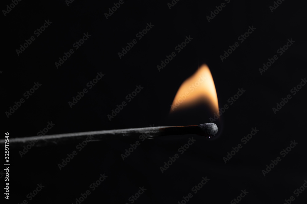 burning match with a bright flame against a black background