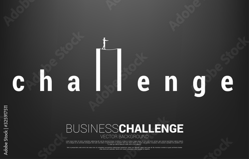 Silhouette of businessman walking on rope walk way on challenge wording.Concept for business risk and challenge in career path