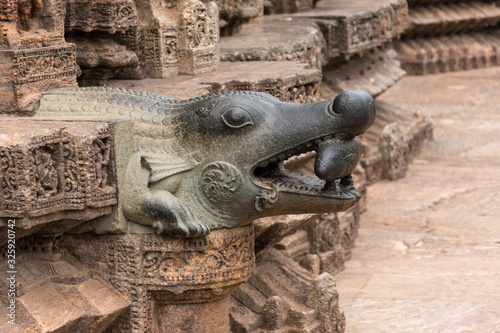 A water outlet in the shape of a crocodile, holding a fish in its mouth photo