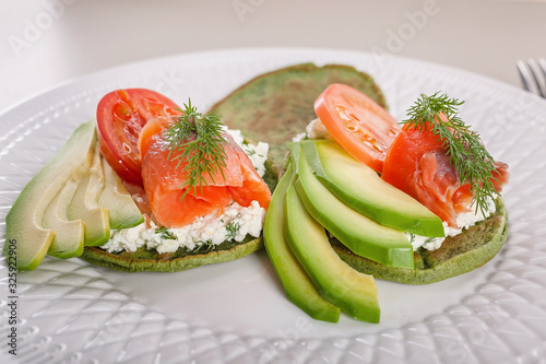 Close-up Pancakes with spinach, curd cheese, avocado and smoked salmon. Tasty and healthy breakfast