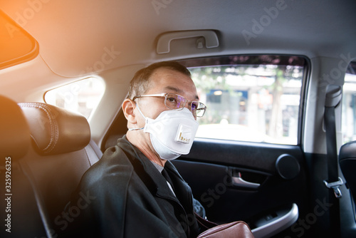 Man wearing spectacles and N95 mask for protect PM 2.5 dust and serious of the air pollution while sitting and waiting for the bus at the bus stop with crutches or support stick in Bangkok Thailand.