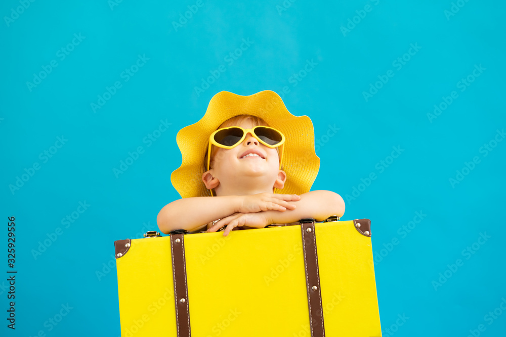 Portrait of happy child with yellow suitcase. Summer vacation concept - obrazy, fototapety, plakaty 