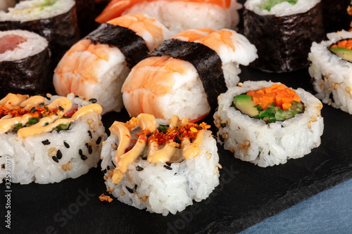 Large sushi set close-up. Maki, nigiri and rolls on a black slate