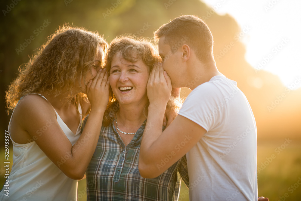Daughter and son whispering secret into mother's ear Daughter and son whispering secret into mother's ear