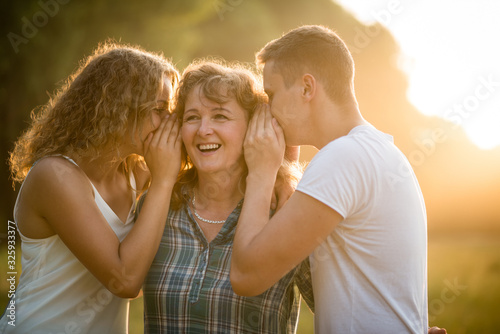 Obraz na plátně Daughter and son whispering secret into mother's ear