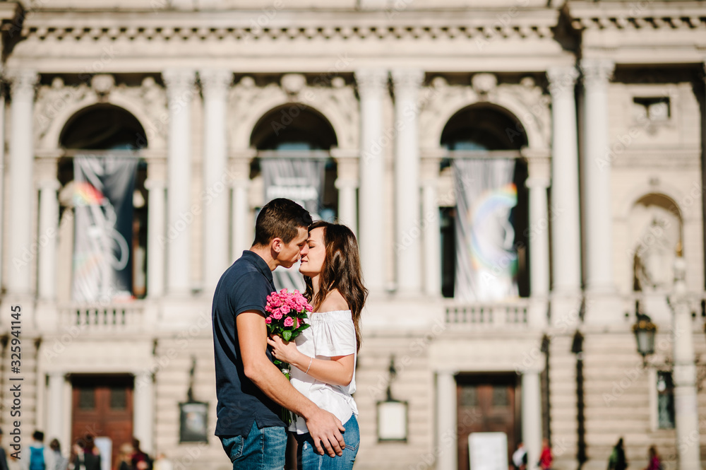 Smiling Young couple with a bouquet of flowers in love hug each other in love outdoors. Love and tenderness, dating, romance. Lifestyle concept.