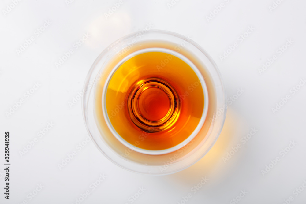 A glass of whiskey stands on a white background. The view from the top A glass of whiskey stands on a white background. The view from the top