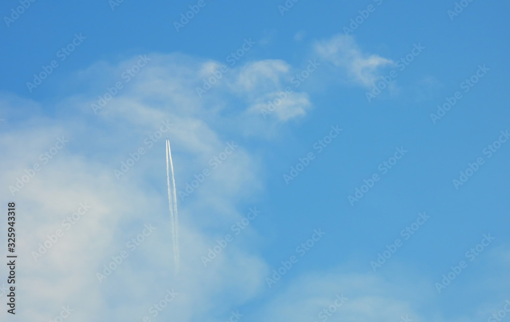Airplane flying in the clear blue sky and contrail against, Engine exhaust contrails forming behind, Jet contrails or trails over blue sky and clouds. Airplane flying in the clear blue sky and contrail against, Engine exhaust contrails forming behind, Jet contrails or trails over blue sky and clouds.