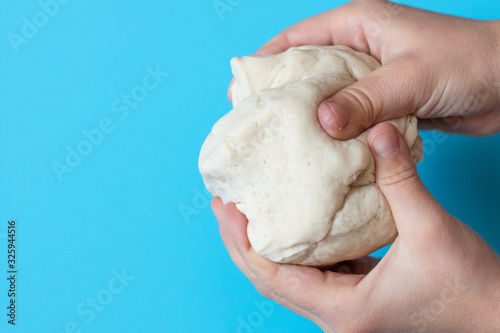 Salt dough for modeling in the hands of a child on a blue background