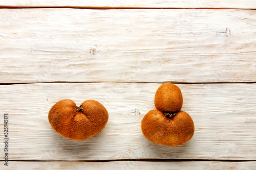 Ugly kiwi fruits on a white wooden background. Fruit or food waste concept. Top view, close-up.