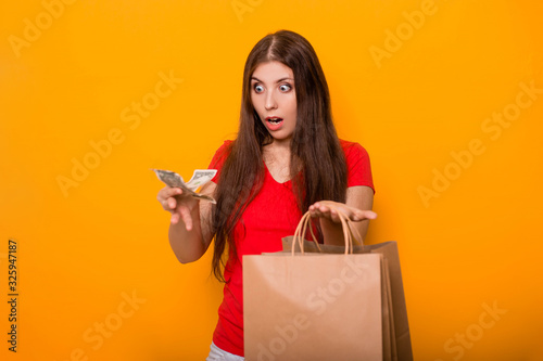 A young, attractive woman with money and packages in her hands, looks at a loss at the remaining money after shopping. photo