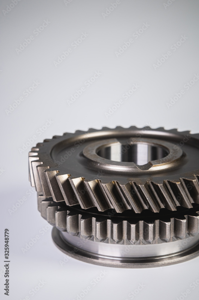 New parts on a gray background. Gears of gear shifting torque transmission. Conceptually mechanical background. Shiny gear box gear teeth New parts on a gray background. Gears of gear shifting torque transmission. Conceptually mechanical background. Shiny gear box gear teeth
