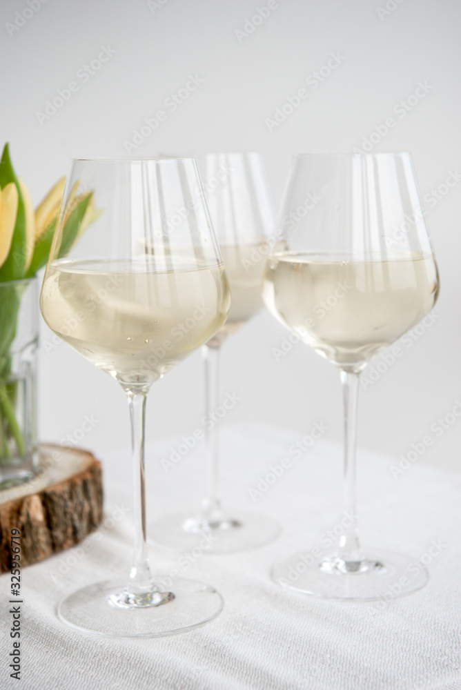 White wine. Dry wine. Glass of wine on the backgound table. Spring flowers. Yellow tulips. White wine. Dry wine. Glass of wine on the backgound table. Spring flowers. Yellow tulips.