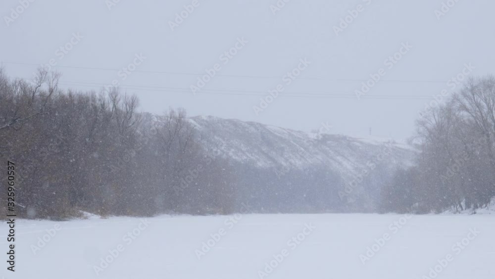 Snowfall on a frozen river with high banks. Camera panning Snowfall on a frozen river with high banks. Camera panning