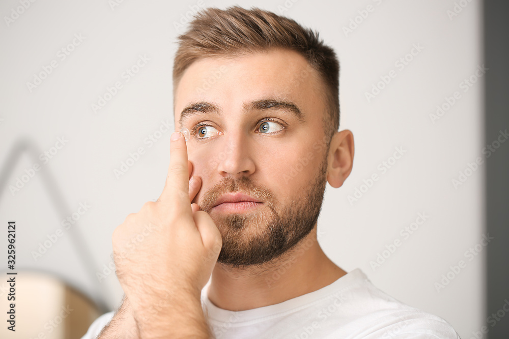 Young man putting in contact lenses at home Young man putting in contact lenses at home