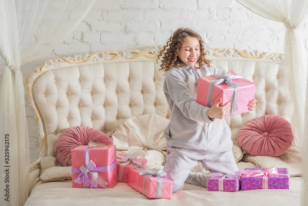 Teen girl on a bed at home with many gift. Celebrating something