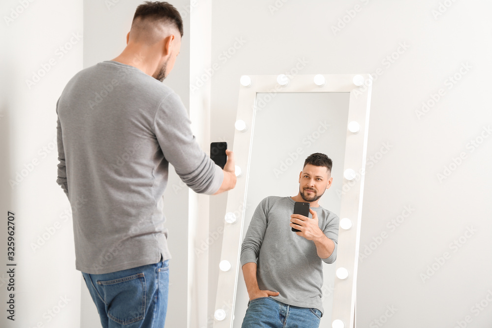 Handsome man taking selfie near mirror at home Handsome man taking selfie near mirror at home