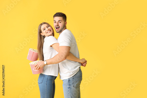 Happy young couple with popcorn on color background © Pixel-Shot