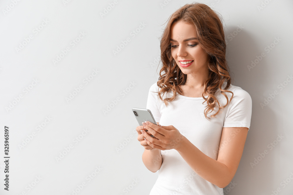 Young woman with mobile phone on light background Young woman with mobile phone on light background