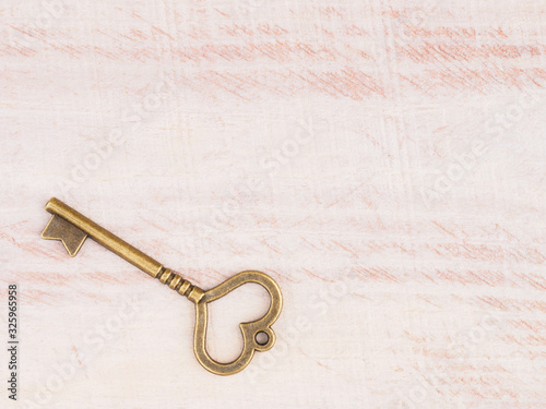 Old bronze antique key on brown wooden background with copy space © zah108
