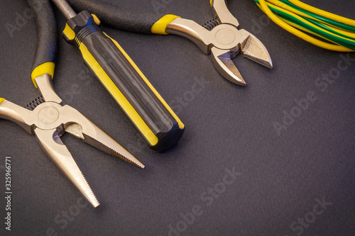Electrician's tools and wire on black background for repairing energized systems or communications